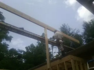 Carpenter setting a ridge beam over a new addition frame — Ice Dam Removal by Roofing Brothers in Gwynn Oak