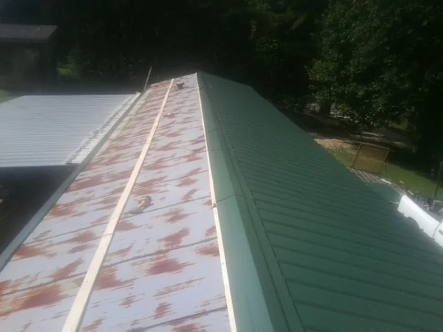 Old rusted panels beside newly installed green metal roofing — Wind Damage Roof Repair by Roofing Brothers in Gwynn Oak