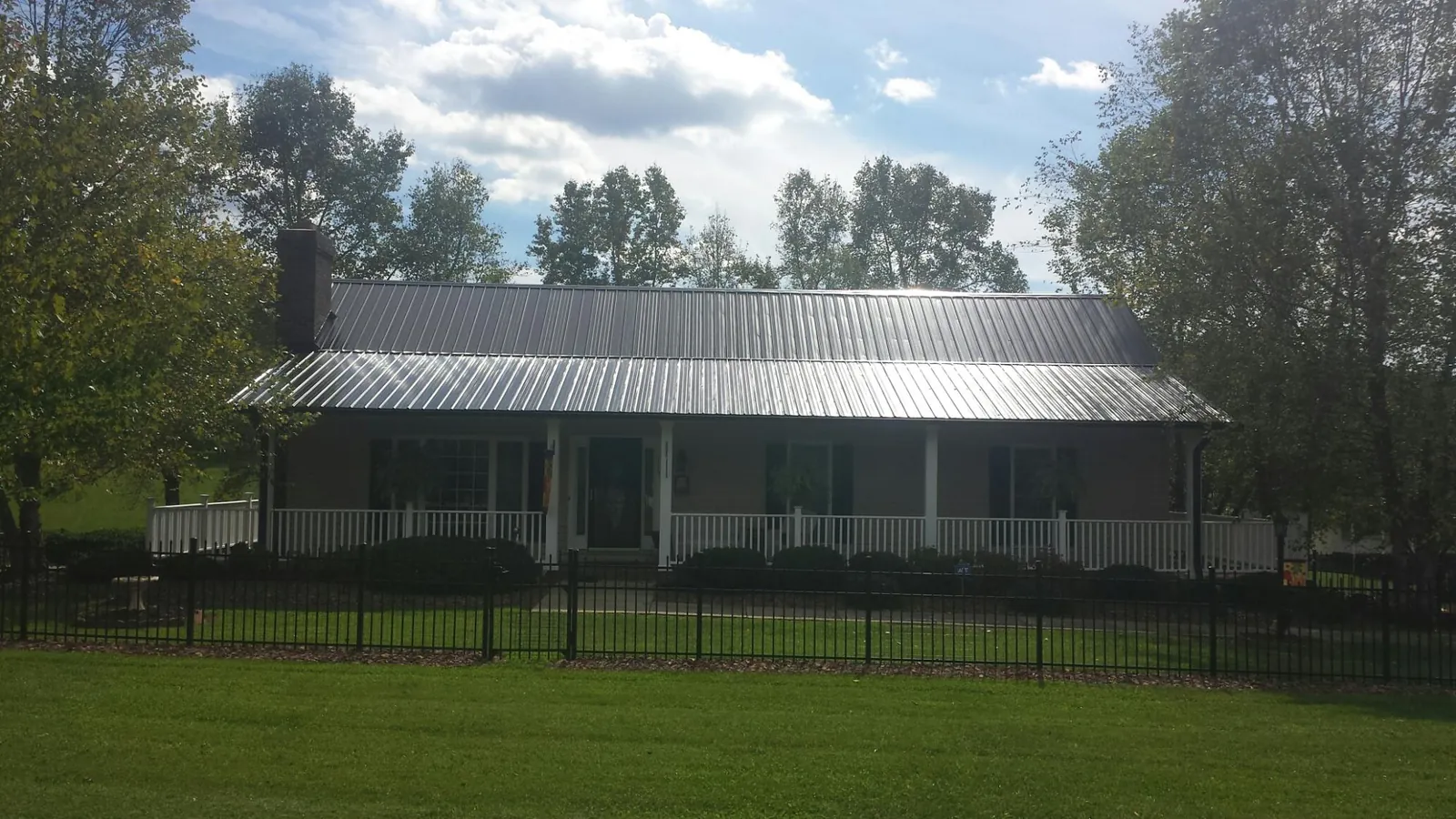 Gray metal roof on a brick ranch with a full width front porch — Gutter Guard Installation work by our crew in Gwynn Oak