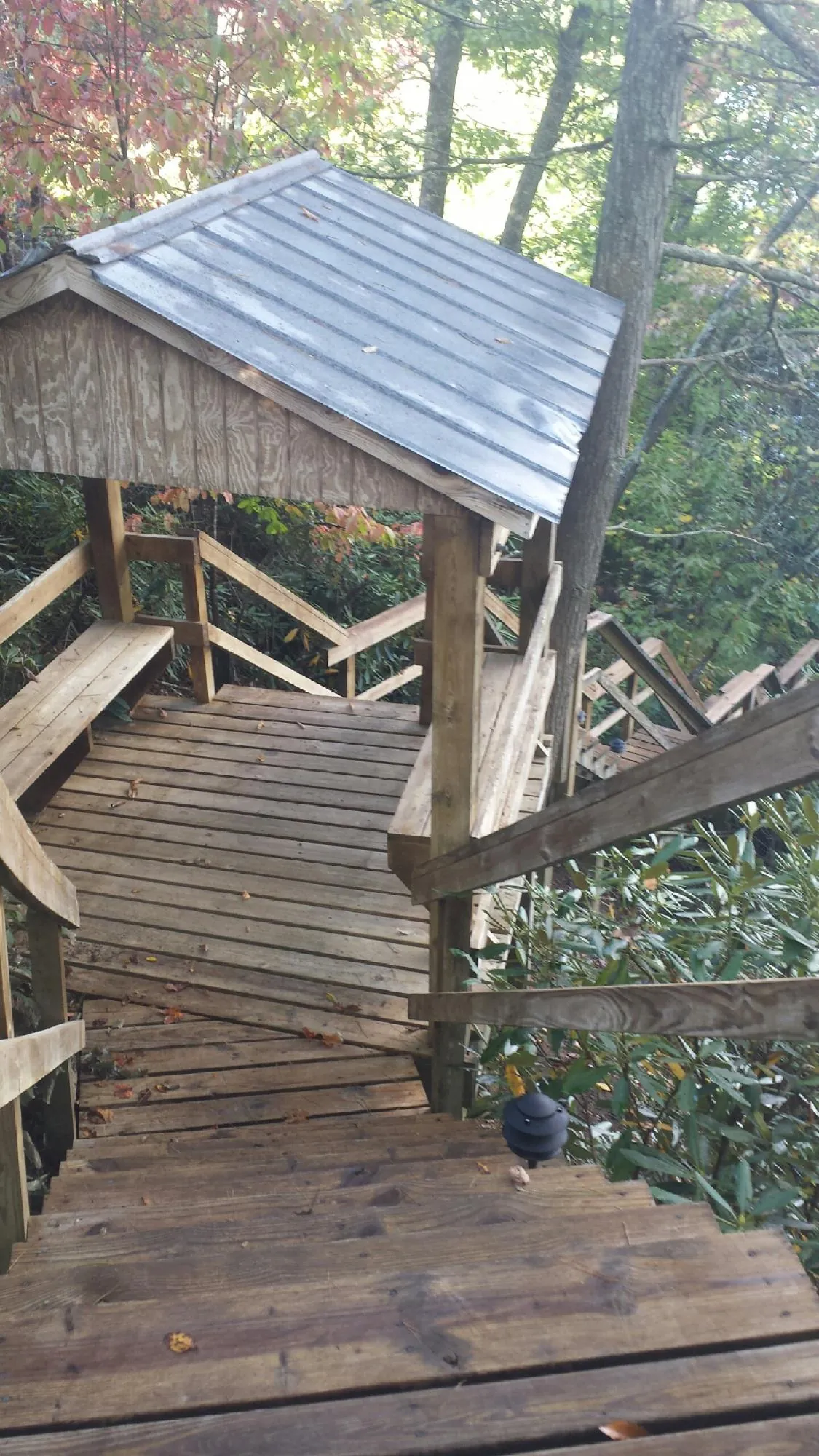 Metal roofed shelter over wooden steps on a wooded walkway — Skylight Repair & Installation work by our crew in Gwynn Oak