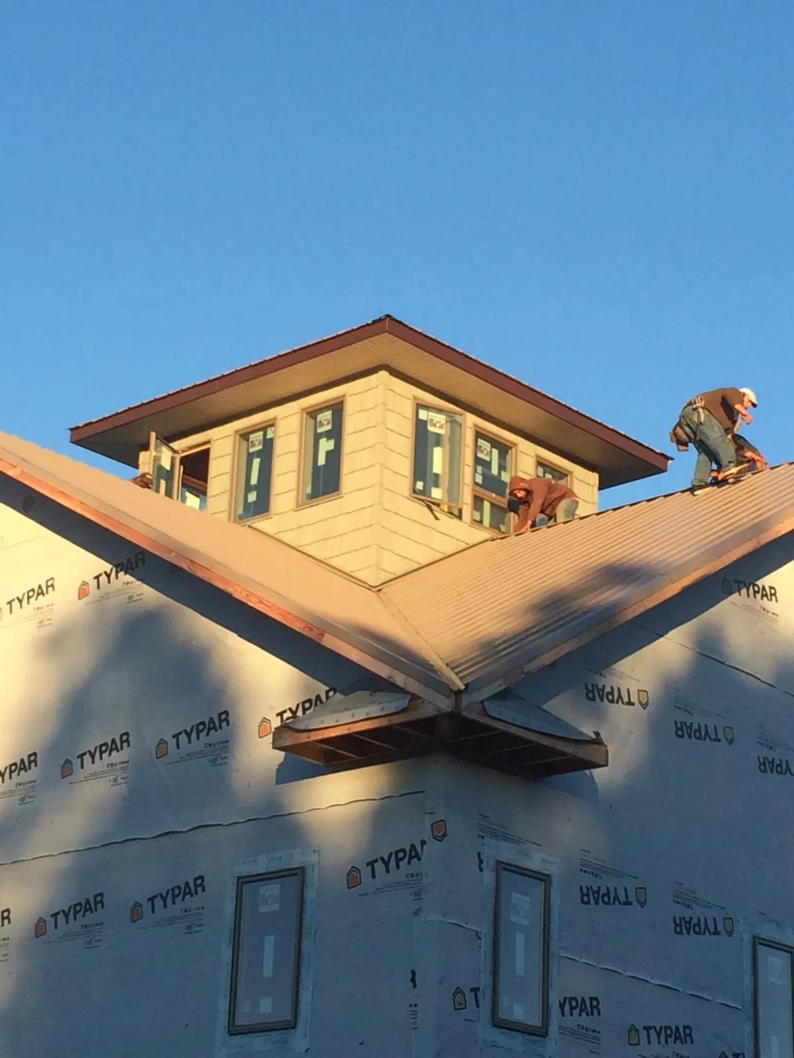 Roofers working around a rooftop cupola on a new metal roof at sunset — Roof Waterproofing in Gwynn Oak by Roofing Brothers